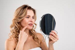Woman observing appearance in mirror in Providence, RI