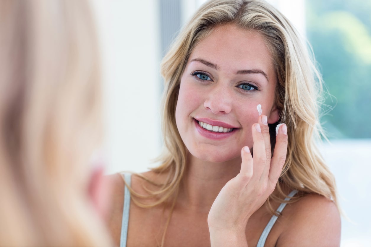 Woman applying skin care product to her face.